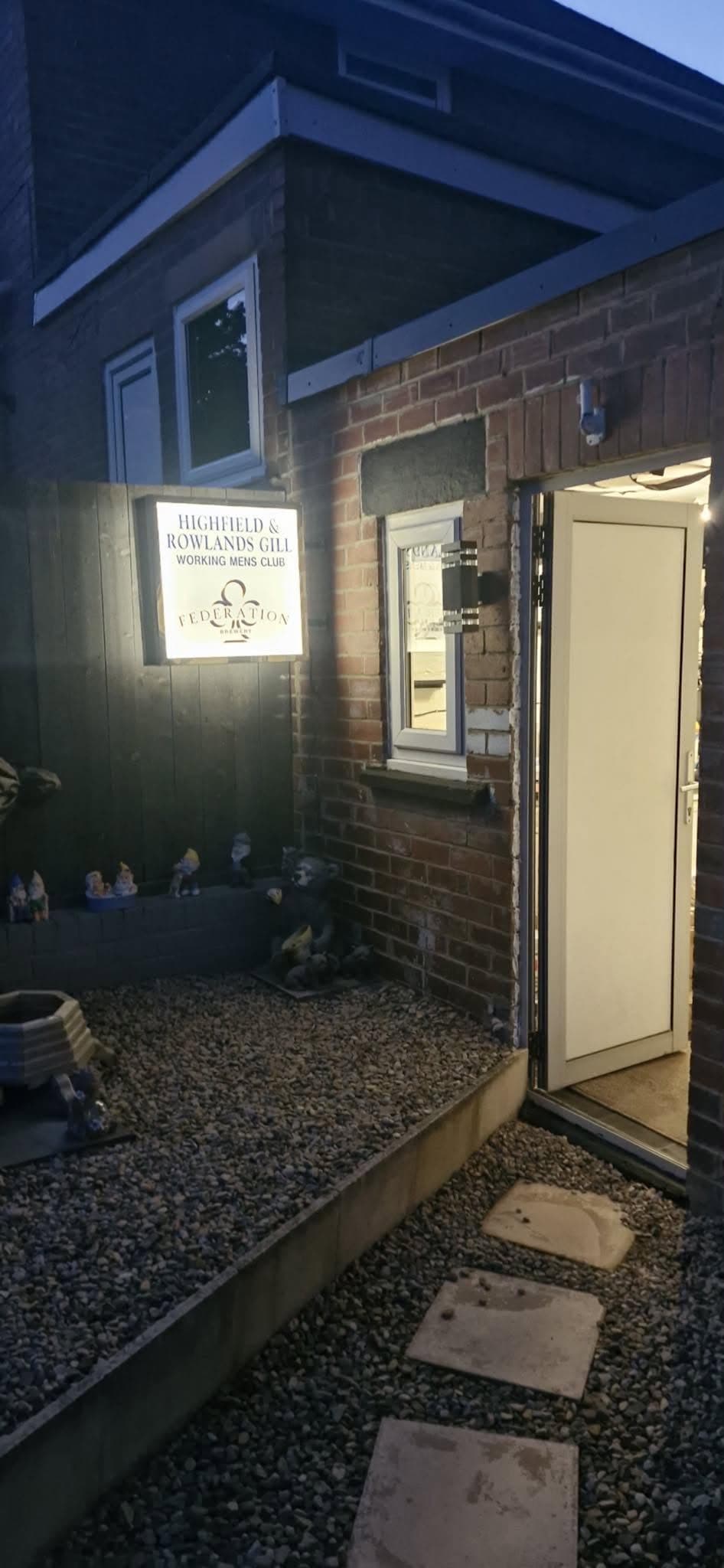 Illuminated wall-mounted sign lighting at a working men's club entrance