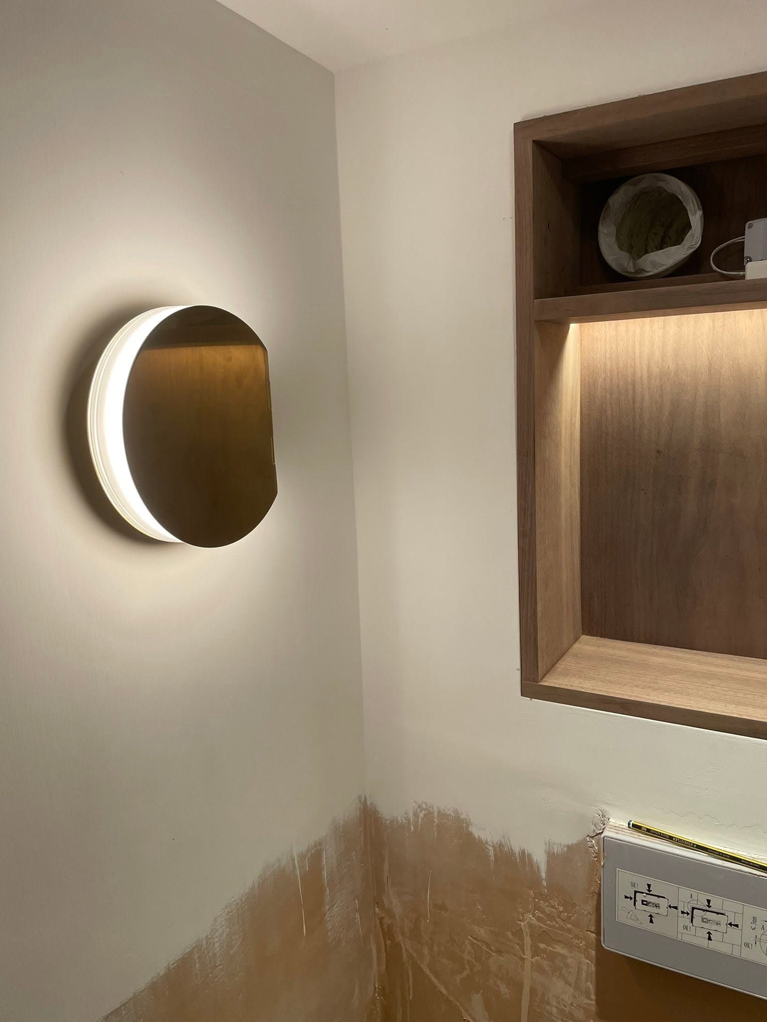 Half-moon LED feature wall light beside an LED-lit walnut display alcove