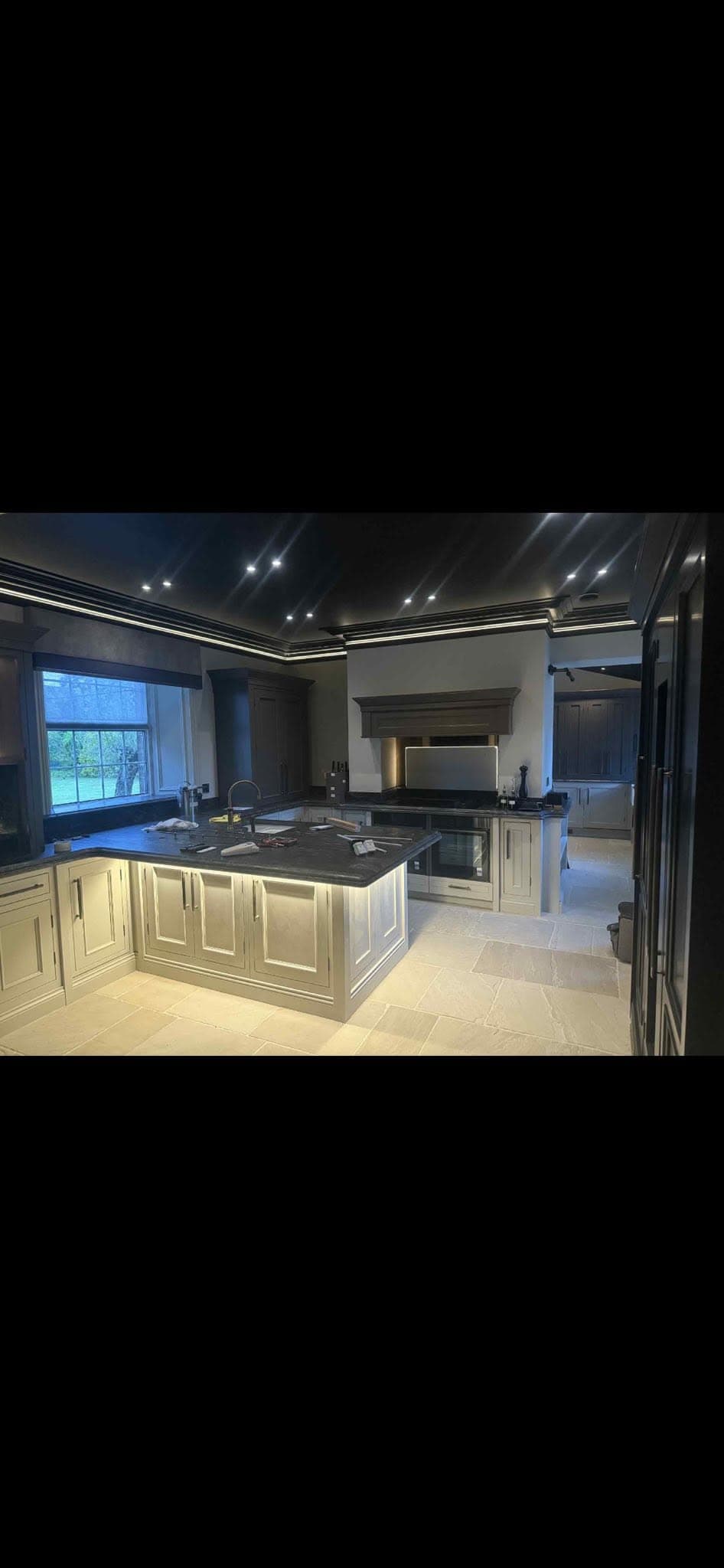 Dramatic luxury kitchen with black lacquered ceiling, LED cornice lighting and recessed downlights throughout