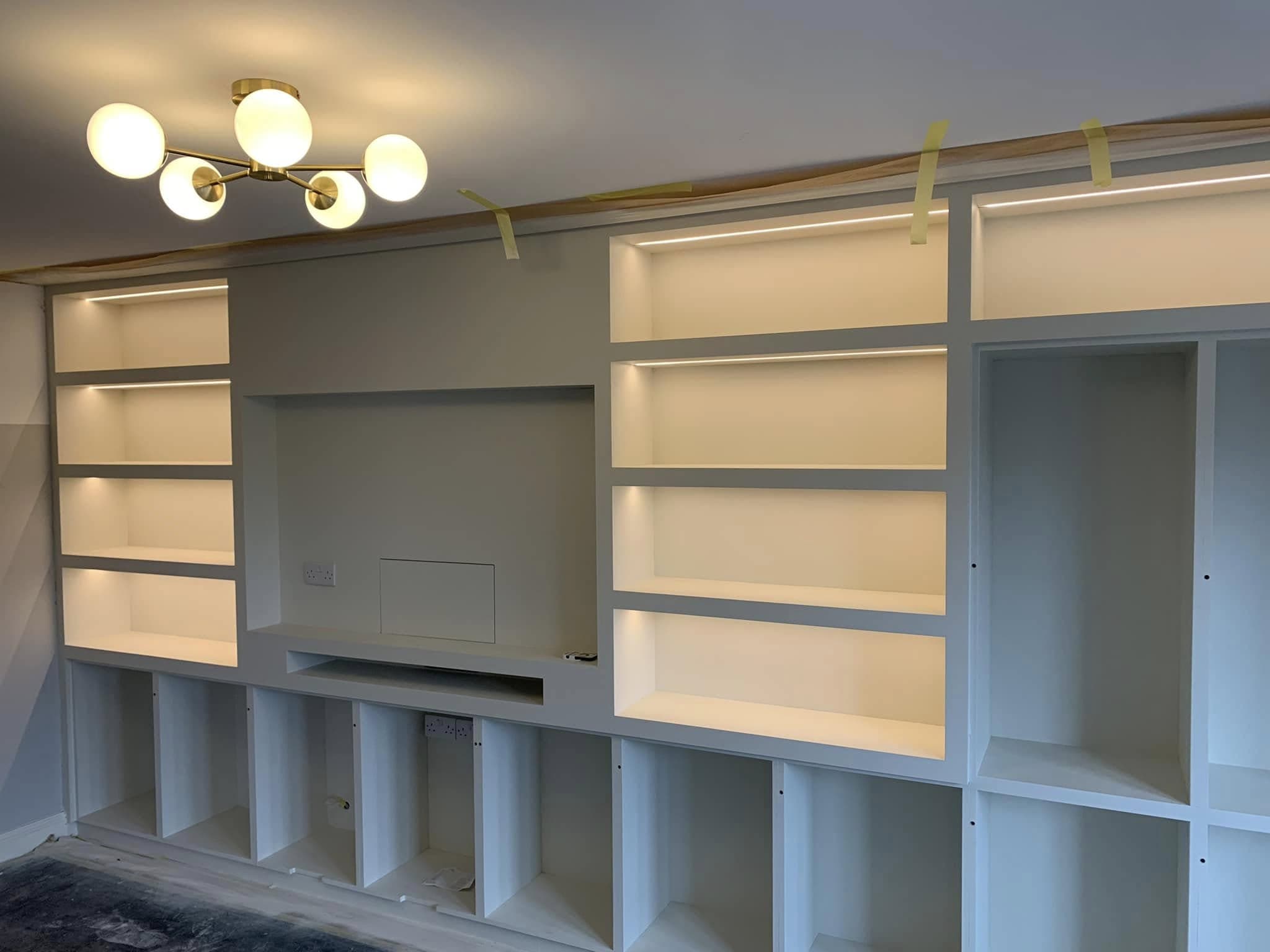 Built-in media wall with LED strip-lit shelving and a feature ceiling light